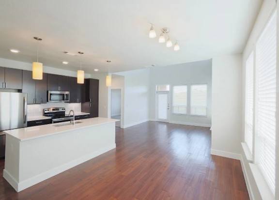 A kitchen with a white counter and wooden floors.