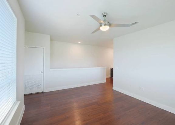 A room with a ceiling fan and wooden flooring.