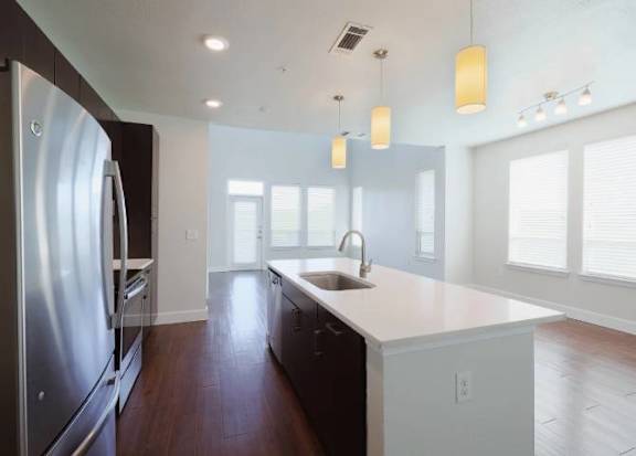 A modern kitchen with a stainless steel refrigerator and wooden floors.