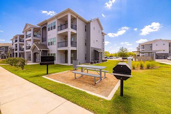 A sunny day at a residential complex with a picnic table and mailboxes.