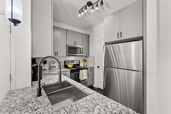 A kitchen with a stainless steel refrigerator and a sink with a black faucet. at Preserve at Rolling Oaks, Texas, 78728