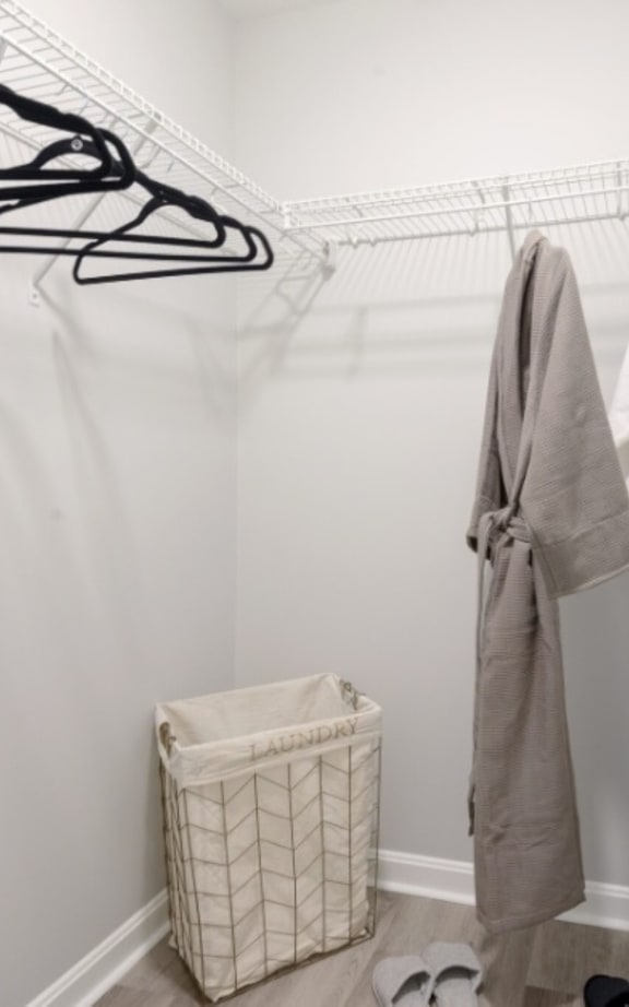 a walk in closet with a basket and hangers