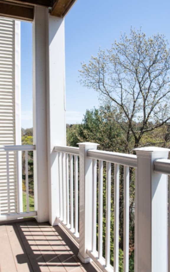 a picture of a balcony with white railing and a tree in the background