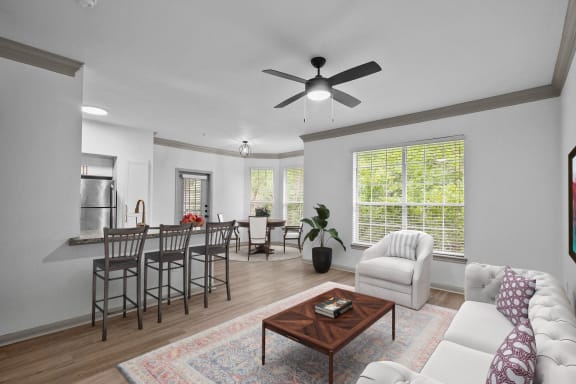 a living room with a ceiling fan and a table with chairs at The Aster Sugar Land, Texas