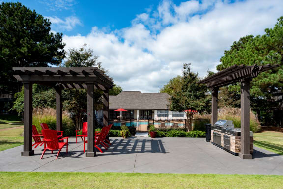 a backyard with a patio with chairs and a grill
