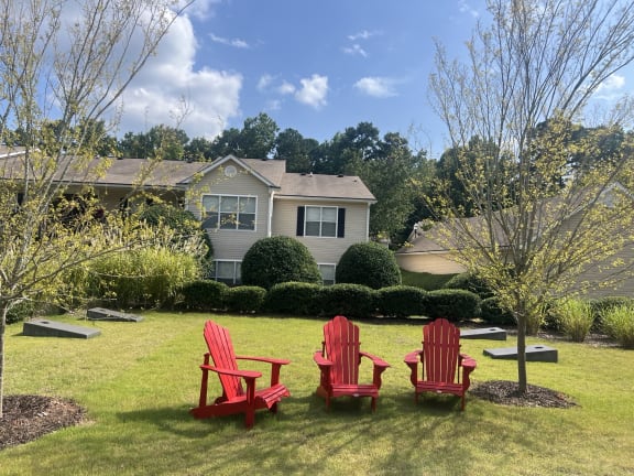 three red chairs sitting in a lawn in front of a house at Addison on Cobblestone, Georgia