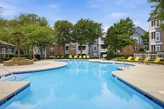 Swimming pool with lounge chairs and apartment buildings at Alden Place at South Square Apartments, Durham