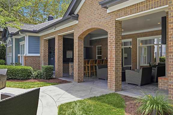 Covered outdoor patio with brick archway and seating at Alden Place at South Square Apartments, North Carolina