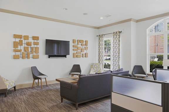 Clubhouse lounge with modern seating and wall mounted television at Alden Place at South Square Apartments, Durham, NC