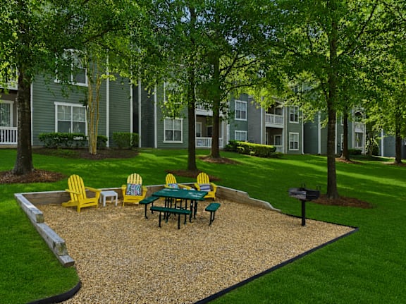 Outdoor picnic area with yellow adirondack chairs and gravel surface at Alden Place at South Square Apartments, North Carolina