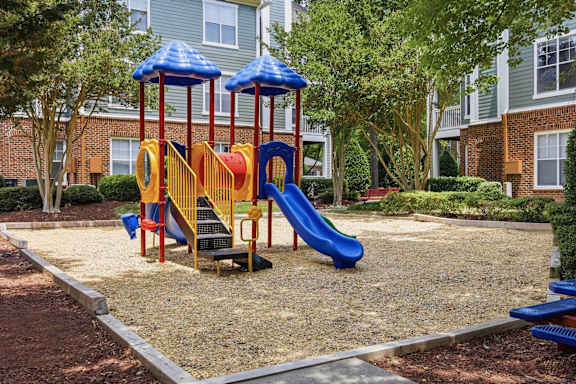 Colorful playground equipment on sand surface at Alden Place at South Square Apartments, Durham, North Carolina