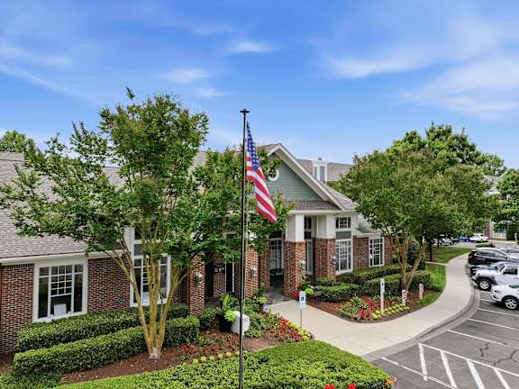 Brick clubhouse entrance with american flag and landscaping at Alden Place at South Square Apartments, Durham, 27707