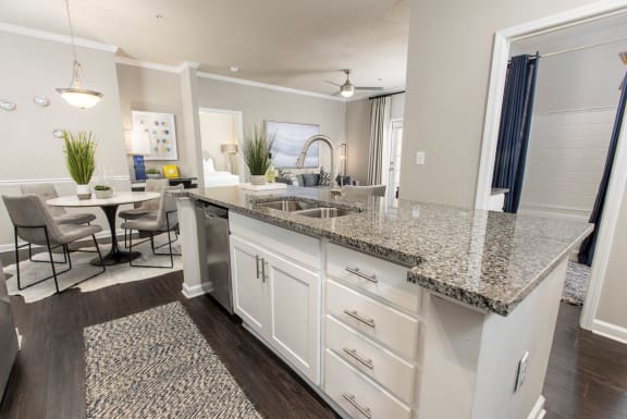 an open kitchen with granite counter tops and a dining room with a table at Ansley at Town Center in Evans GA