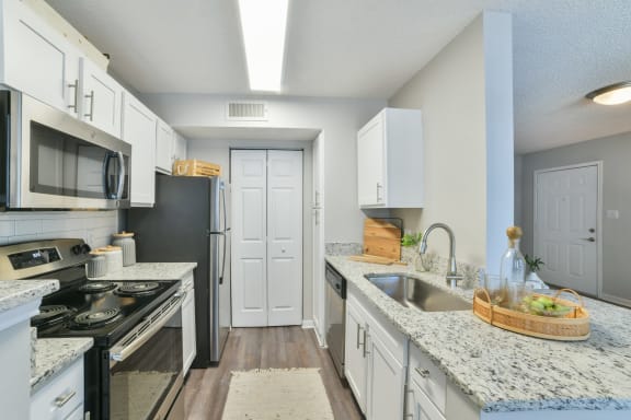 a kitchen with white cabinets and black and white appliances at Arbors Harbor Town, Memphis, TN, 38103