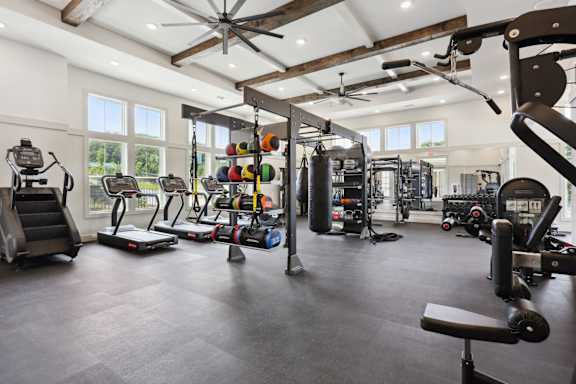 A spacious gym with a variety of equipment including treadmills, weights, and a bench press at Arcadia Cartersville Apartments, Cartersville, Georgia