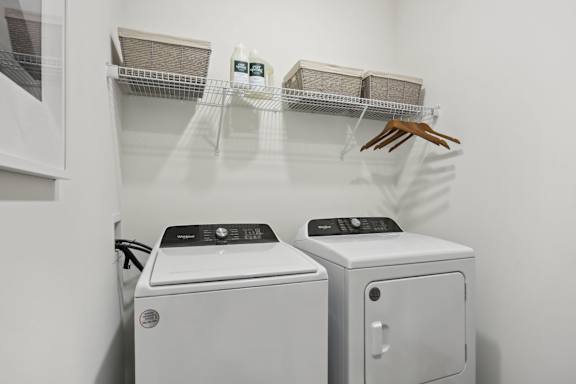 A laundry room with a washer and dryer and a shelf with baskets and a handbag at Arcadia Cartersville Apartments, Georgia, 30121