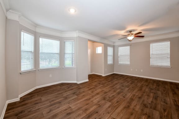 an empty living room with a ceiling fan and windows at Artesian on Westheimer, Houston, Texas