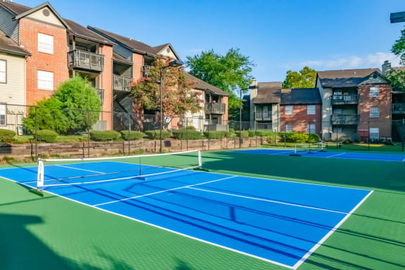 two tennis courts with apartments in the background