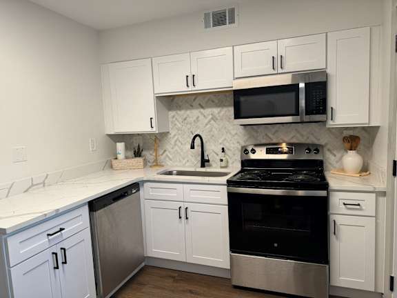 A kitchen with white cabinets and a black stove top oven.at Century Apartments, Tennessee, 38117