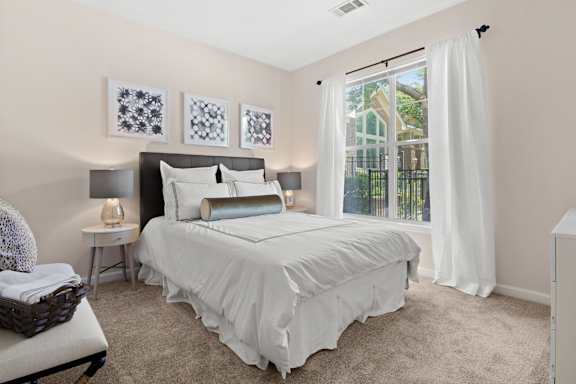 Bedroom with white bedding and large window at Alden Place at South Square Apartments, Durham, 27707