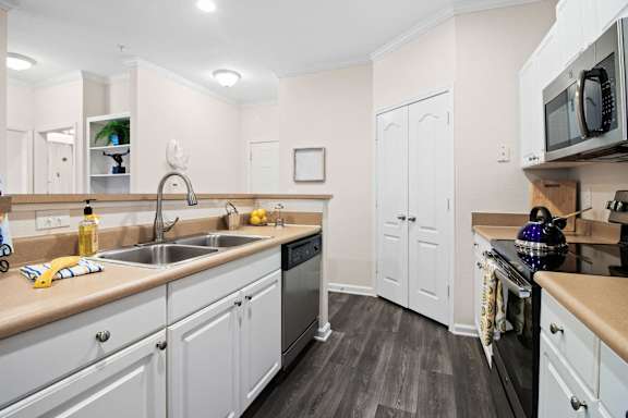 Galley kitchen with white cabinets and stainless steel appliances at Alden Place at South Square Apartments, North Carolina