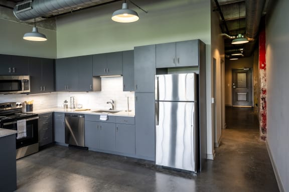 a kitchen with gray cabinets and stainless steel appliances