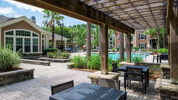 A patio with a table and chairs under a wooden pergola.