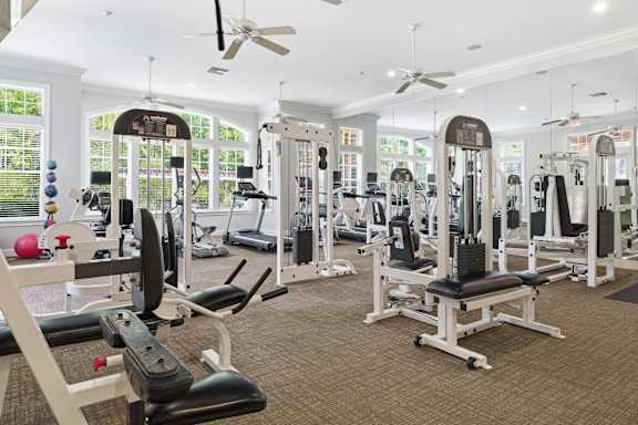 A gym with a variety of equipment including treadmills, weights, and exercise machines.