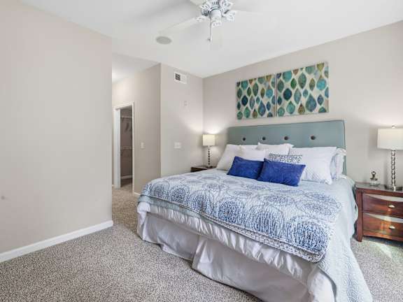 A bedroom with a bed, nightstand, and a ceiling fan.