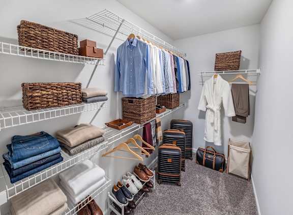 A walk-in closet with clothes and baskets on shelves.