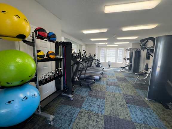 A gym with a variety of equipment including weights, exercise balls, and treadmills at Enclave at Wolfchase Apartments, Tennessee