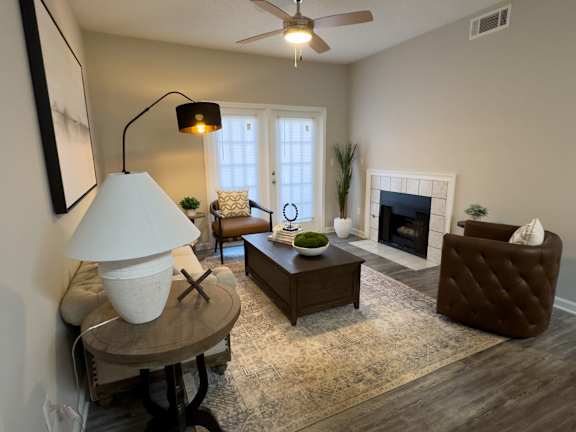 A living room with a fireplace, a chair, a table, and a lamp at Enclave at Wolfchase Apartments, Memphis, TN