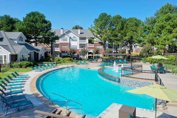 A large swimming pool with a waterfall and lounge chairs at Enclave at Wolfchase Apartments, Memphis, Tennessee