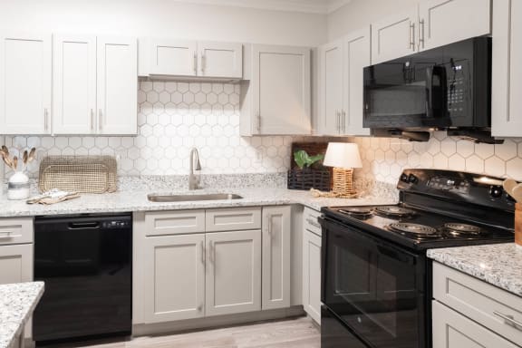 a kitchen with white cabinets and black appliances at Appling Lakes, Cordova