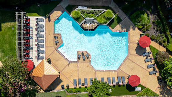 An aerial view of a swimming pool surrounded by sun loungers and umbrellas.