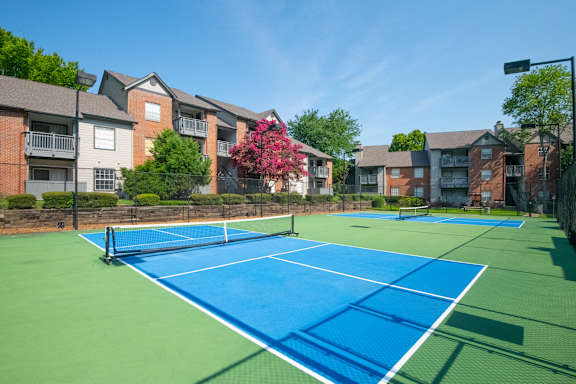 A tennis court surrounded by apartment buildings.