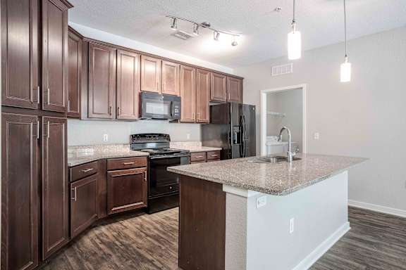 A kitchen with cabinets and a granite countertop at Park Place Oviedo Apartments, Oviedo, FL
