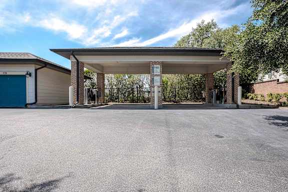 A parking lot with a covered parking area and a blue garage door at Park Place Oviedo Apartments, Oviedo, 32765