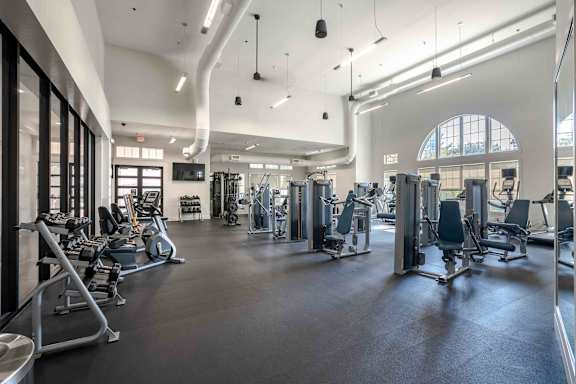 A spacious gym with a variety of equipment and a large window at Park Place Oviedo Apartments, Florida, 32765