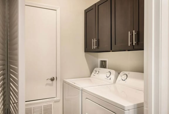 a laundry room with white appliances and dark cabinets &#xA0;at Arlo Luxury homes Apartments, Arkansas