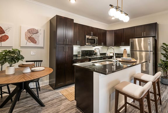 spacious kitchen with stainless steel appliances and a breakfast bar with a wooden table and chairs &#xA0;at Arlo Luxury homes Apartments, Little Rock, AR,72210