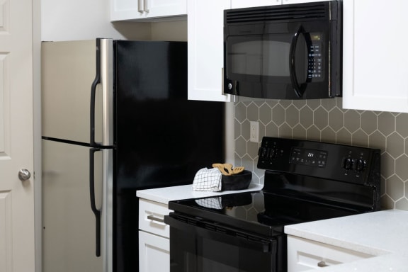 a kitchen with white cabinets and black appliances at Ashby at Ross Bridge, Hoover, AL 35226