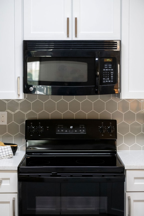 a kitchen with white cabinets and a black stove and microwave at Ashby at Ross Bridge, Alabama, 35226