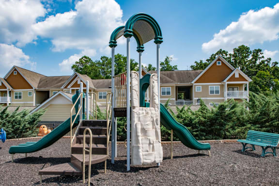 a playground with a slide and climbing equipment in front of a row of houses at Ashby at Ross Bridge, Alabama