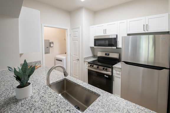 A kitchen with a granite countertop and stainless steel appliances. at Henley at Mirror Lake, Villa Rica, Georgia