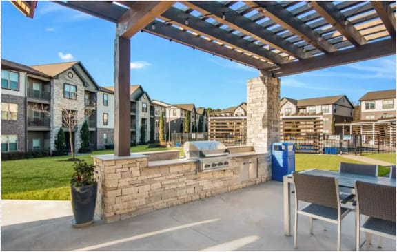 a covered patio with a grill and a table and chairs at The McKenzie Park Apartments, Little Rock, 72223