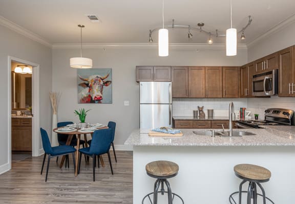 a kitchen and dining area with a table and chairs and a refrigerator at The McKenzie Park Apartments, Little Rock