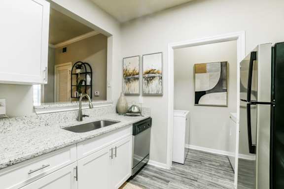 A kitchen with a black refrigerator and white cabinets.