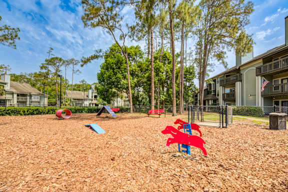 A playground with red and blue slides in the foreground and apartment buildings in the background.