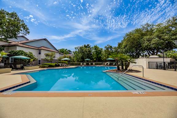 A large outdoor swimming pool surrounded by trees and a house.